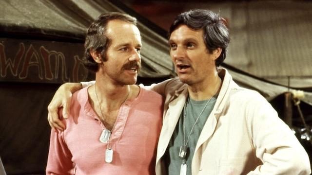 Mike Farrell and Alan Alda, portraying B.J. Hunnicutt and Hawkeye Pierce, share a moment of camaraderie in the beloved series M*A*S*H. Farrell joined the cast in 1975, and the two became fan favorites for their chemistry both on and off-screen.